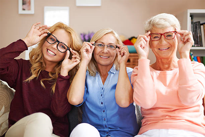 Three ladies wearing glasses sit on a couch together.